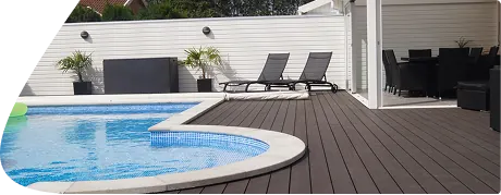 Dark WPC decking beside a swimming pool with lounge chairs