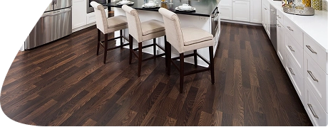Dark espresso wood flooring planks in white kitchen.
