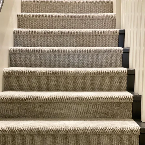 Textured grey linear loop carpet on wooden stairs