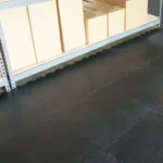 Black interlocking floor mats under warehouse shelving