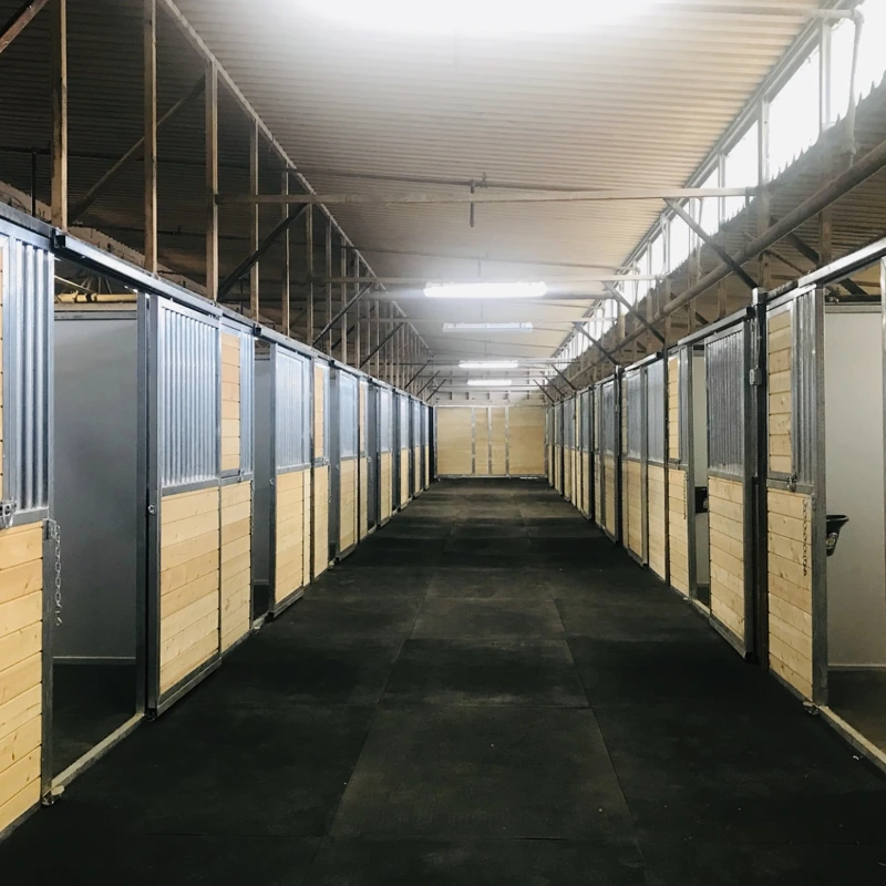 Black rubber flooring in a horse stable aisle.