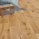 Close-up of natural oak flooring with a radio and throw blanket.