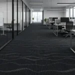 Dark charcoal carpet tiles with a flowing, wavy grey pattern in an open-plan office.
