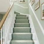 Green stair runner looking down white staircase