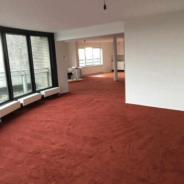 Wall-to-wall terracotta red carpet flooring in a spacious modern building interior.