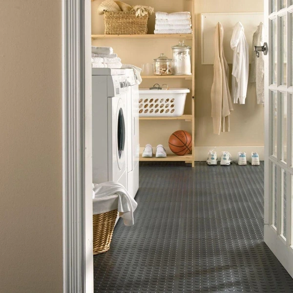 Dark grey coin-patterned rubber flooring mat in a laundry room