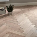 Light oak herringbone flooring with a houseplant.
