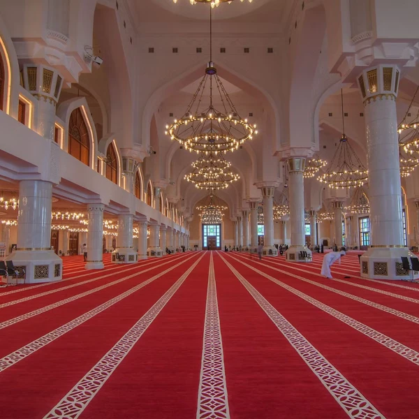 Red mosque carpet with white prayer lines in a grand Islamic prayer hall