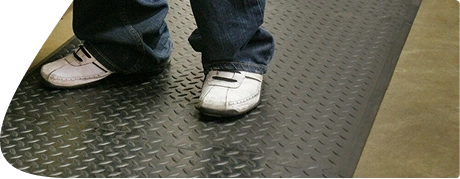 Person in white sneakers standing on diamond-plate rubber mat