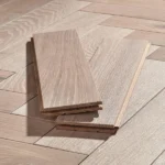 Two light oak flooring planks in herringbone pattern.