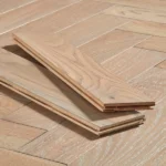 Two light oak flooring planks showcasing a herringbone pattern.