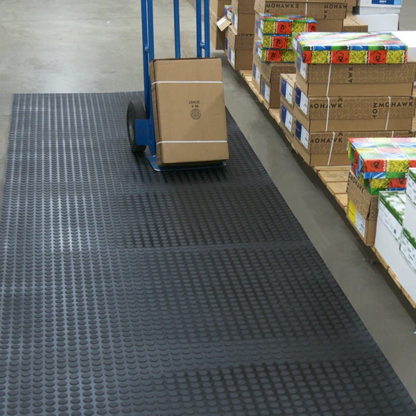 Dark grey coin-pattern rubber runner mat in a warehouse aisle.