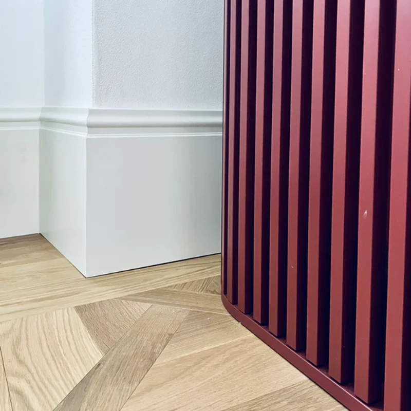 High white MDF skirting board near red wood panel