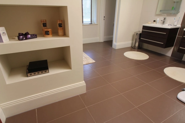 High white MDF skirting board on brown bathroom tiles