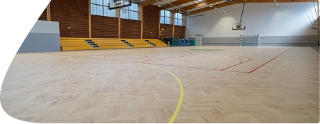 Light-colored wooden sports flooring with a herringbone pattern