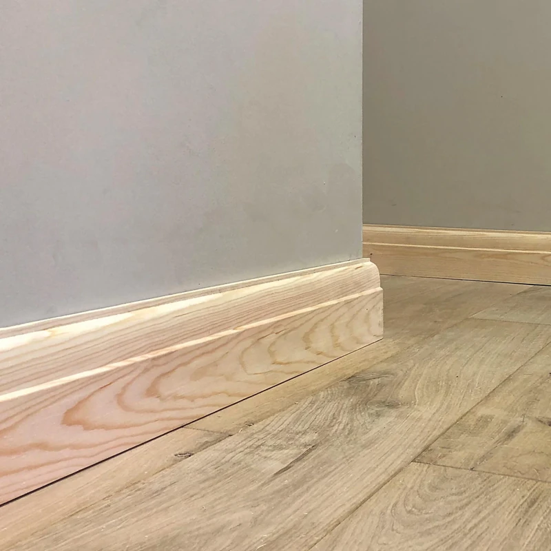 Moulded pine skirting board around a wall corner.