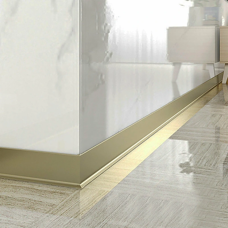 Silver metal baseboard on gray wall and wood floor