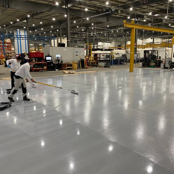 Workers applying grey factory epoxy floor coating finish