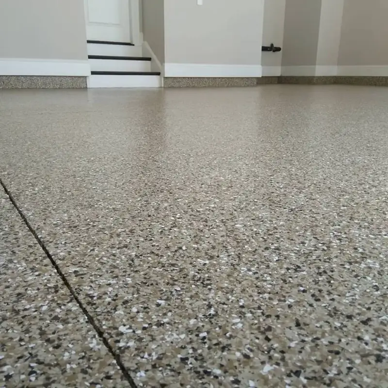 beige and earth-toned speckled epoxy floor finish is shown in a garage setting.