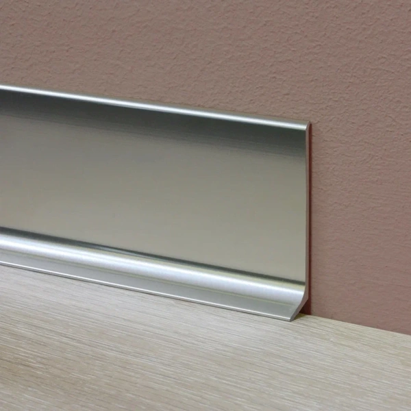 close-up view of a brushed metal skirting board installed against a textured wall